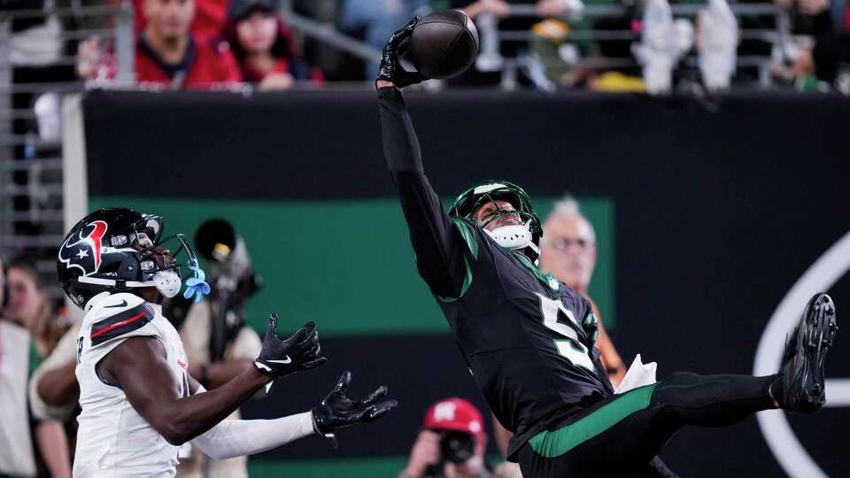 New York Jets wide receiver Garrett Wilson (5) makes a 26-yard touchdown catch against Houston Texans cornerback Kamari Lassiter (4) during the second half of an NFL football game Thursday, Oct. 31, 2024, in East Rutherford.