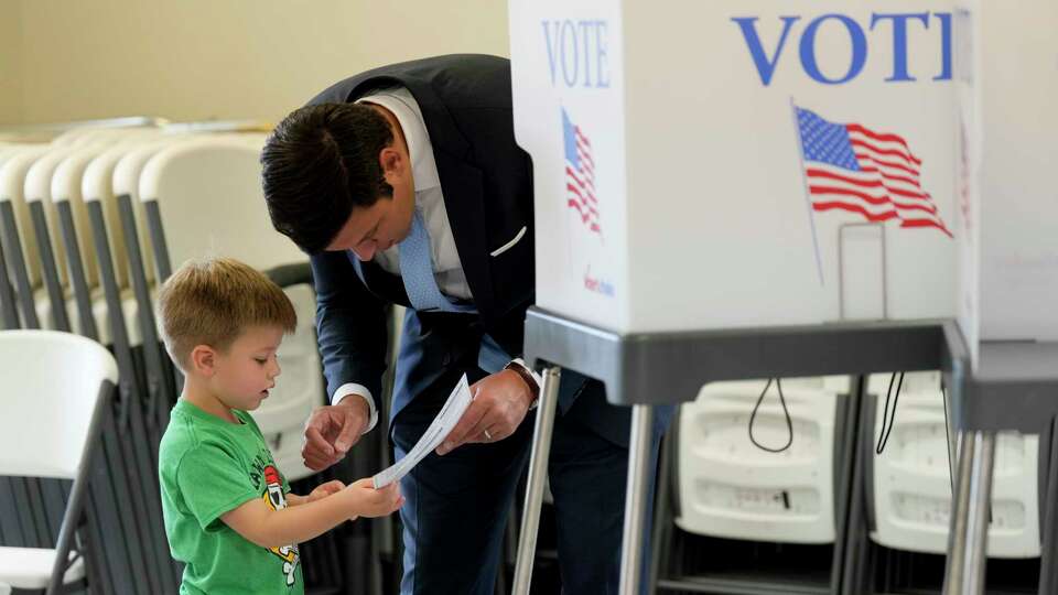 Zeb Smathers, shows a ballot to his 4-year-old son, Stone Smathers, while voting, Tuesday, Nov. 5, 2024, in Canton, N.C. (AP Photo/George Walker IV)