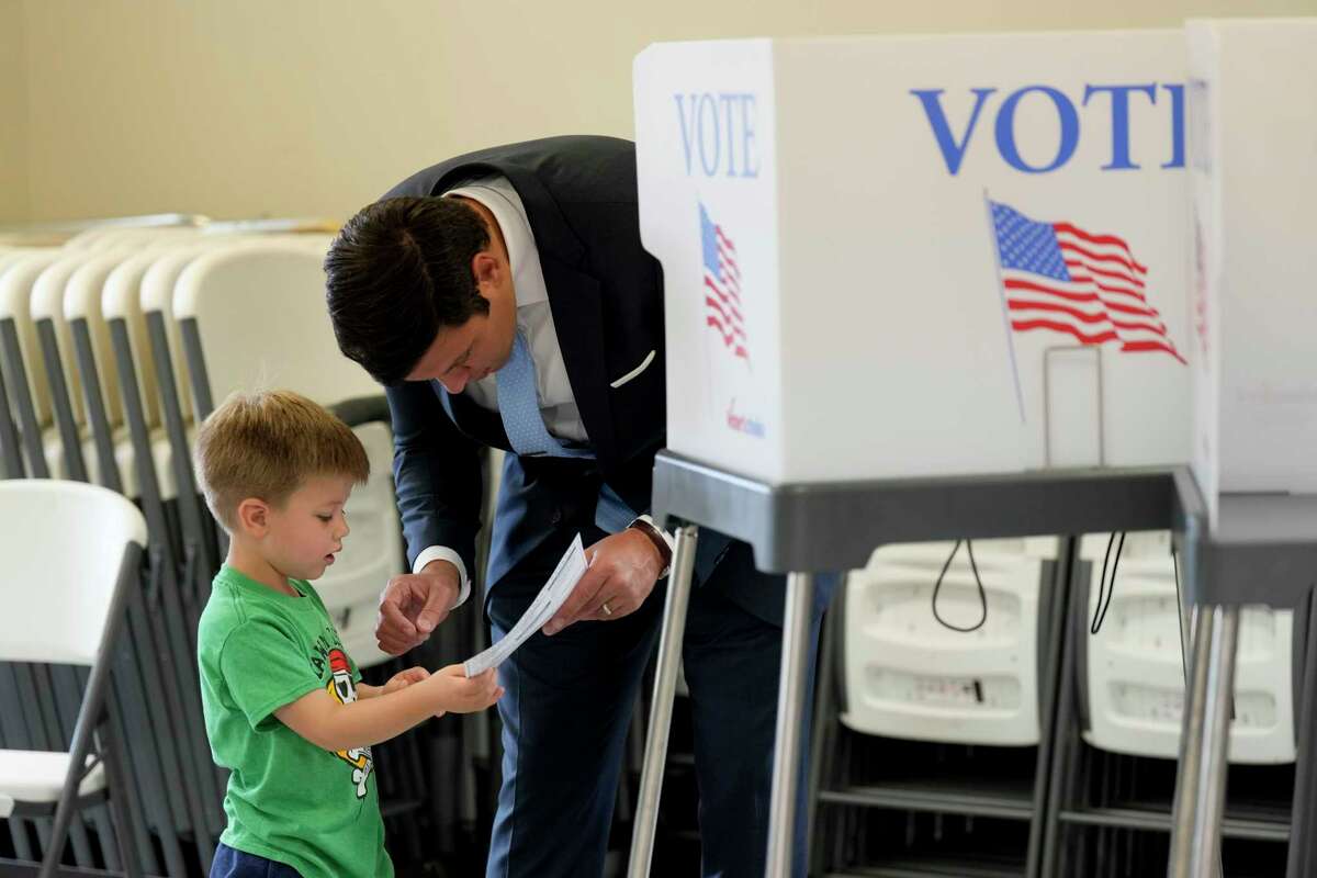 Zeb Smathers, shows a ballot to his 4-year-old son, Stone Smathers, while voting, Tuesday, Nov. 5, 2024, in Canton, N.C. (AP Photo/George Walker IV)