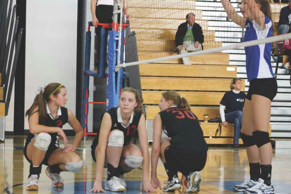 New Canaan's Gwen VandeGraaf, left, Rebecca Evensen, center, and Melissa Tweed prepare for a Rams' serve during the second game Tuesday afternoon, while Darien's Bella Carerra stands tall at the net.