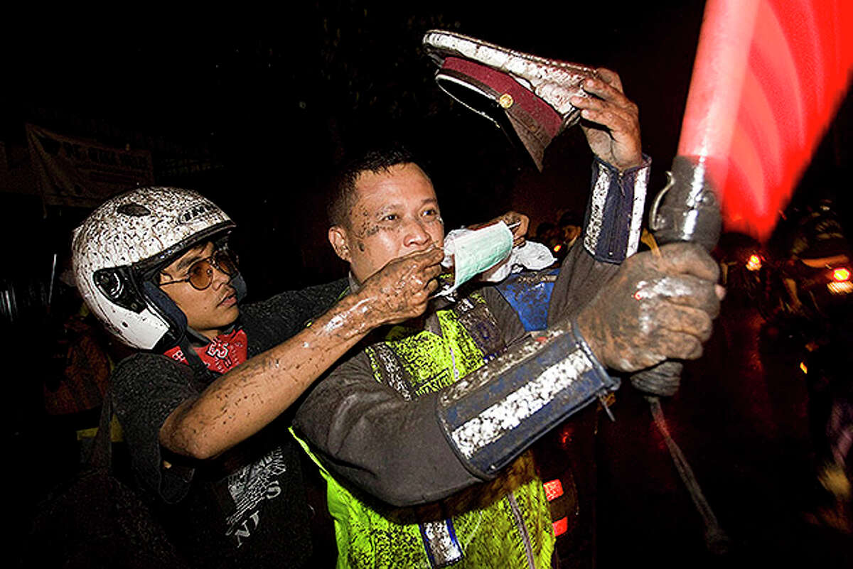 YOGYAKARTA, INDONESIA - NOVEMBER 05: A volunteer wear the face mask to police as stand guard following another eruption of Mount Merapi, in Central Java on November 5, 2010 near Yogyakarta, Indonesia. The eruption claimed the life of at least one man and injured several others from a village on the slope of the volcano that was not evacuated. Over 70,000 people have now been evaculated with the danger zone being extended again to over 20km as the volcano continues to spew ash and volcanic material. (Photo by Ulet Ifansasti/Getty Images)