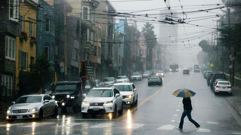 A pedestrian with an umbrella crosses the intersection at Fulton Street under heavy rain in San Francisco on Saturday, Jan. 06, 2024.