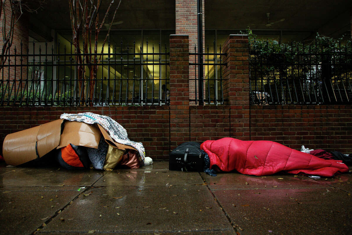 Two homeless people sleep in the rain outside The Beacon on Monday, Jan. 31, 2022, in Houston.