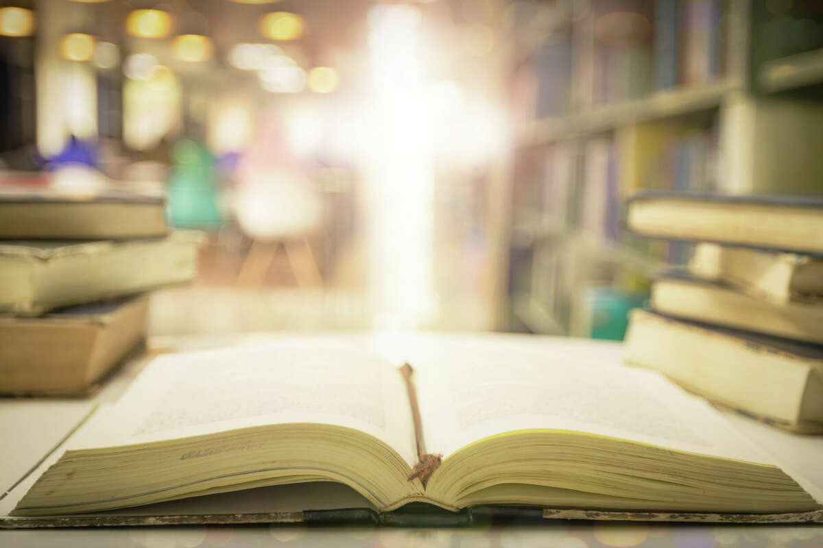 Opening book of Holy Bible with text on blurred cross background