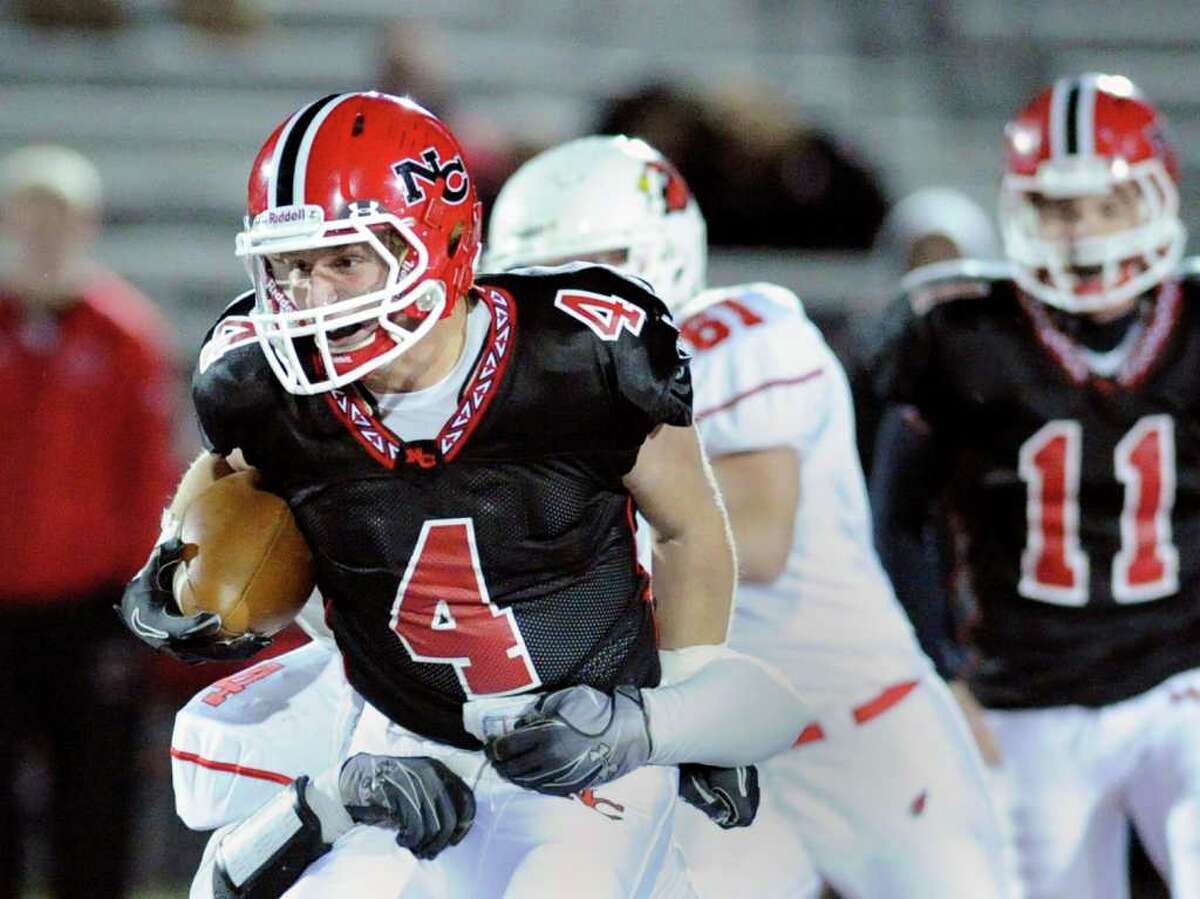 Wide receiver Kevin Macari of New Canaan High School, # 4, runs through Greenwich High School defender Kyle Camacho, also #4, during first half action of High School football game between Greenwich High School vs. New Canaan High School at New Canaan High School, Friday night, Nov. 5, 2010. At right for New Canaan is Ryan Shullman, # 11, Nick Pennella, # 61 of Greenwich High School is at center of photo.