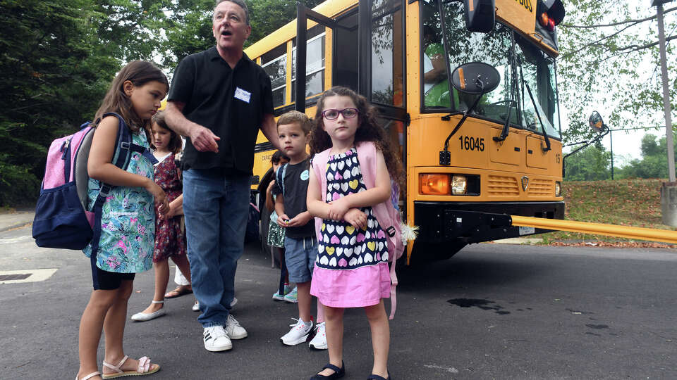 Lee Mansy, a paraprofessional, helps direct students as they arrive by bus for the first day of school at Coleytown Elementary School, in Westport, Conn. Aug. 30, 2022.