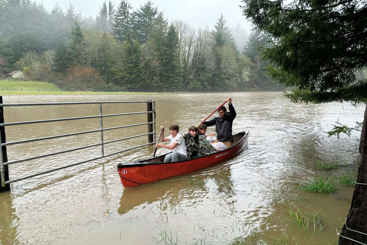 Bret Reinhart and three of his kids paddling across Freshwater Creek in the aftermath of a flooding event. 