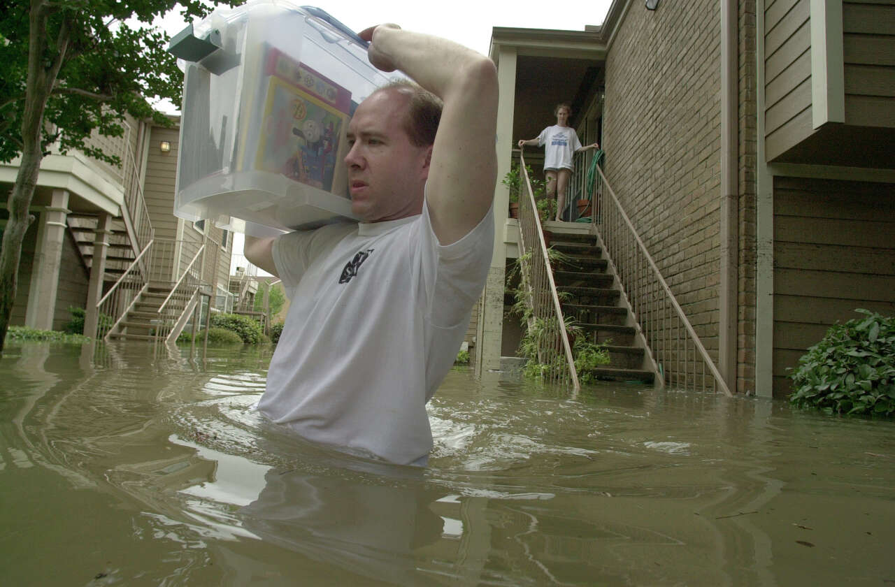 THE GREAT FLOOD OF 2001 -- As his wife Katherine looks on, Mike Frazier carries a box of wedding photos and other valuables through high water as he prepares to evacuate the White Oak Apartments as White Oak Bayou spills into Heights the complex Saturday, June 9, 2001 after heavy rains from the remnants of Tropical Storm Allison inundated Houston, TX flooding a vast majority of the metropolitain area. (Smiley N. Pool/Chronicle) 06/9/01 HOUCHRON CAPTION (06/10/2001): As his wife, Katherine looks on, Mike Frazier carries their wedding photos and other valuables through high water as he evacuates the White Oak Apartments in the Heights. HOUCHRON CAPTION (07/15/2001): While his wife, Katherine, watches, Mike Frazier carries a plastic crate of belongings through waist-deep water as he moves out of the flooded White Oak Apartments. White Oak Bayou, which flooded adjoining neighborhoods and I-10, crested near Ella at almost 68 feet - about 16 feet above the 100-year flood level - at 4:15 a.m. June 9. By the time Frazier moved out of his apartment, the bayou's level had dropped to about 62 feet.