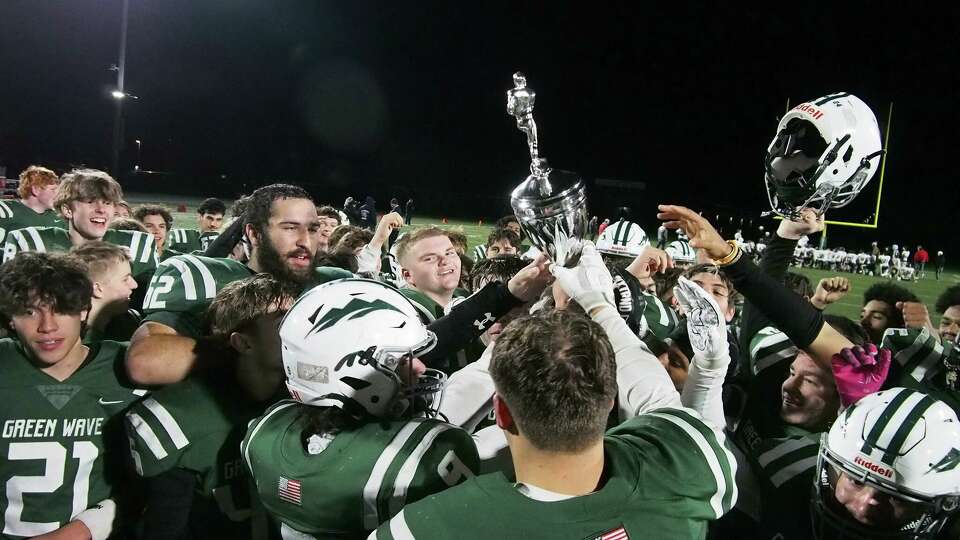 Members of the New Milford football team celebrate with the Candlewood Cup after beating New Fairfield in high school football action in New Milford on Tuesday, Nov. 26, 2024. 