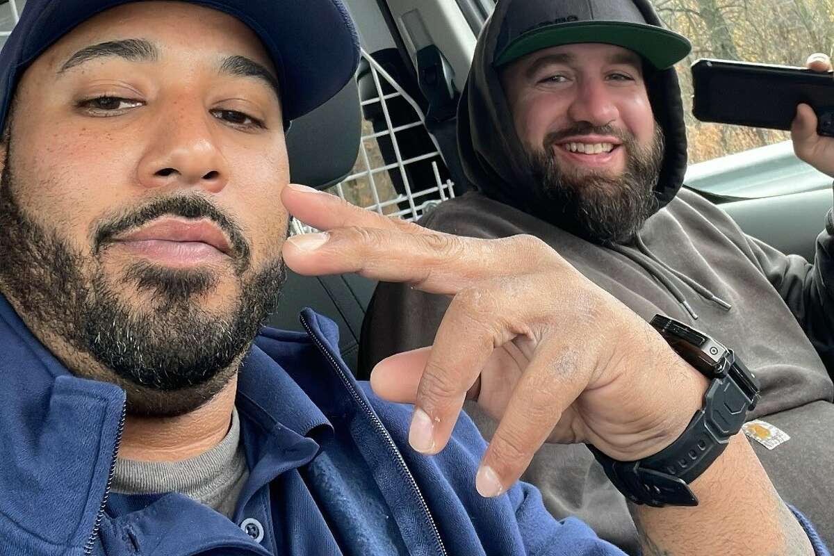 Luis Arce, left, and a tanker driver, Chris (who did not want his last name published), sit in Arce's work van as first responders work at the scene of a fire on Interstate 91 Friday that destroyed the cab of the truck Chris was driving. Arce said Chris was still by the tanker when he urged him to get away and the two hopped into Arce's vehicle and backed well away.