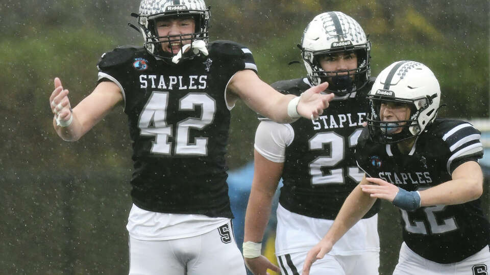 Staples' Davis Crandall (42), Jarett DeLuca (23) and Jack Stoler (22) celebrate after scoring a safety in Staples' 27-0 win over Greenwich in the FCIAC high school football Thanksgiving Day game at Staples High School in Westport, Conn. Nov. 28, 2024.