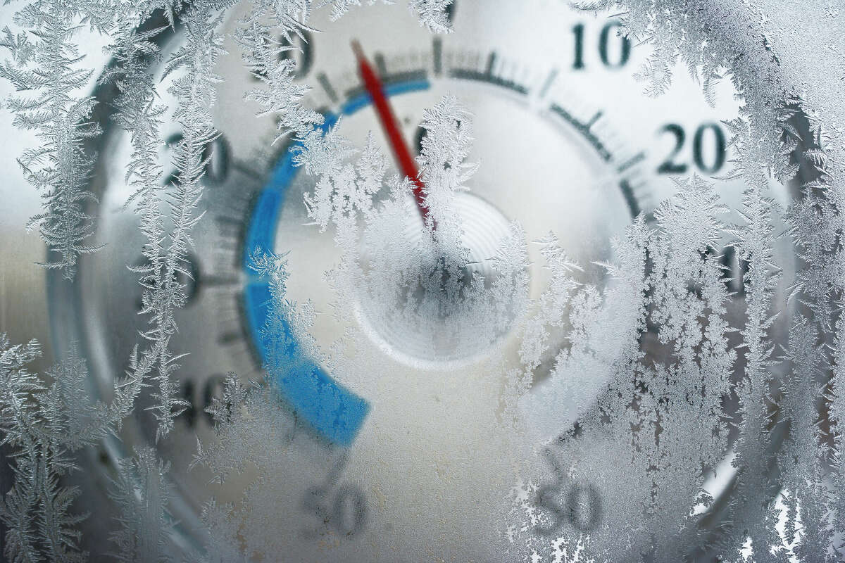 Thermometer for icy window shows the temperature of - 6 degrees Celsius. Red arrow on a blue field. The image is slightly blurry. Frost on the window in focus.