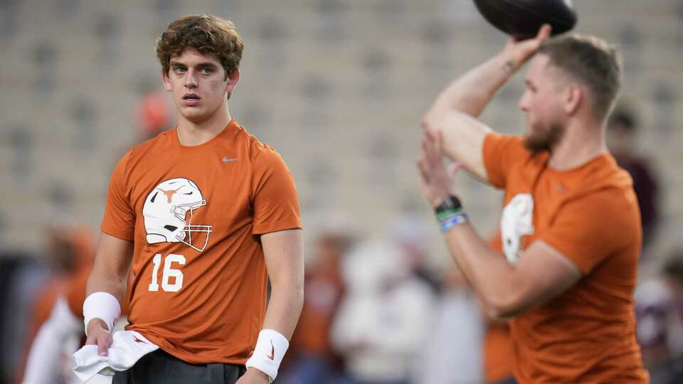 Texas quarterback Arch Manning, left, watches as quarterback Quinn Ewers warm up before an NCAA college football game at Kyle Field, Saturday, Nov. 30, 2024, in College Station.