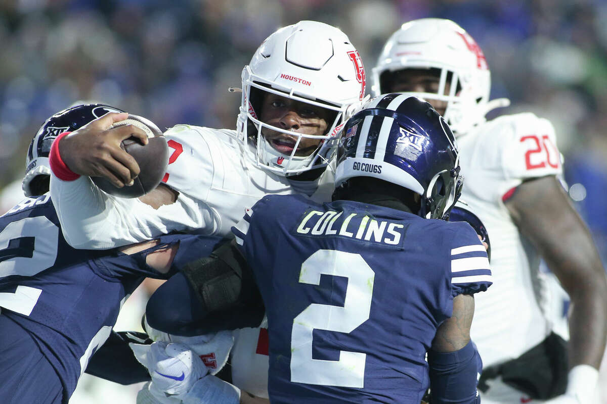 Zeon Chriss of the Houston Cougars pushes into the endzone for a touchdown against Tommy Prassas and Marque Collins of the Brigham Young Cougars during the second half of their game at LaVell Edwards Stadium on November 30, 2024 in Provo, Utah. 