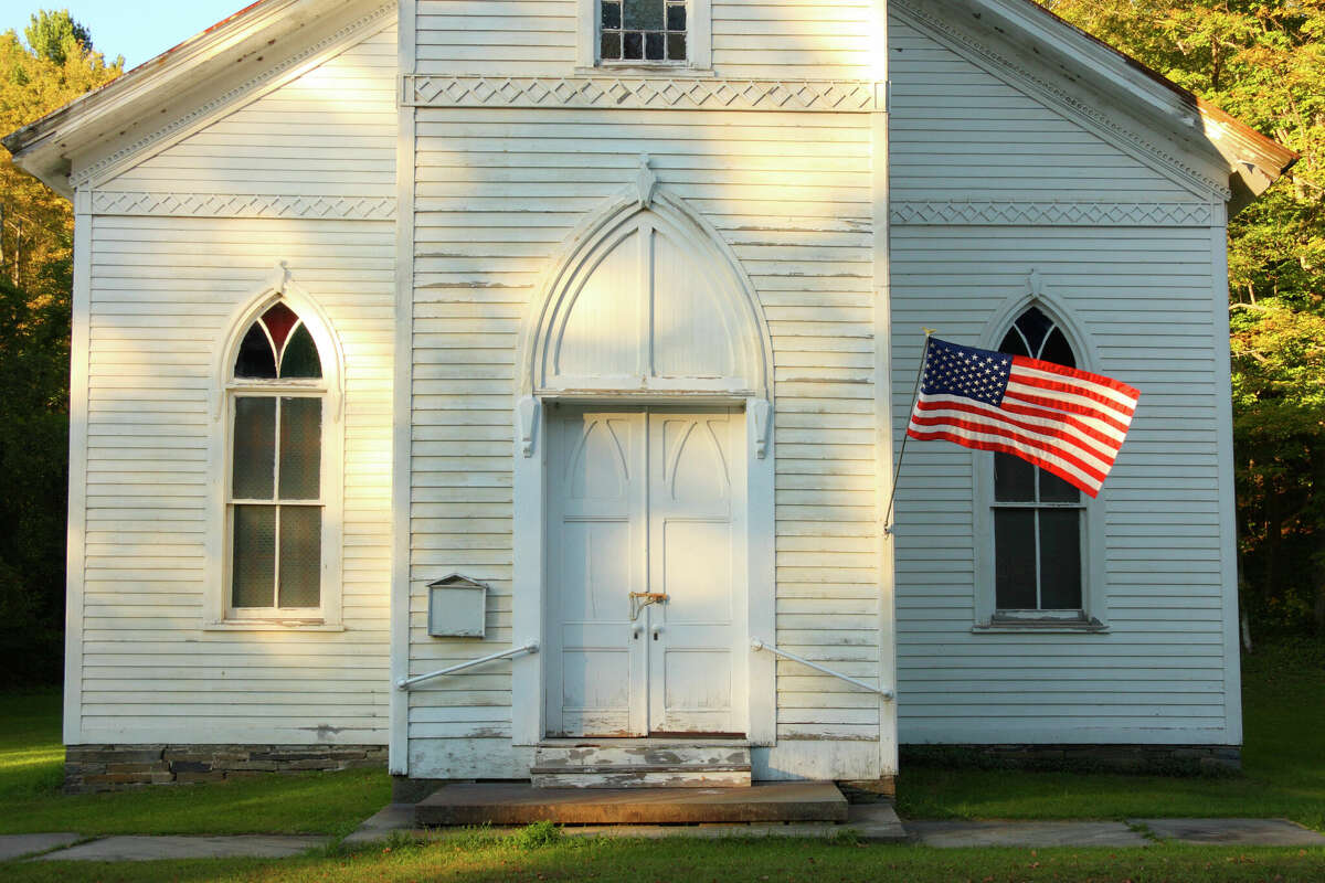 Flag waving in front of old church on summer afternoon.