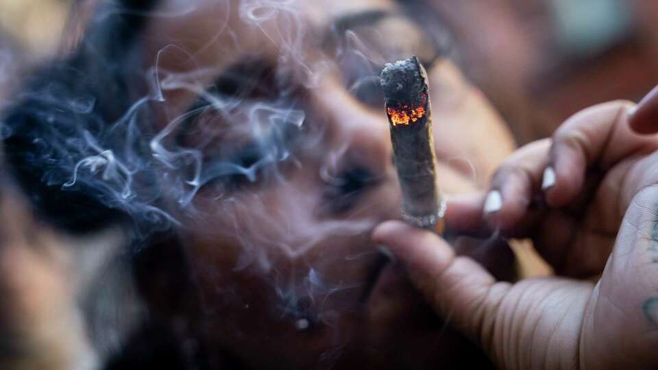 FILE - A person smokes cannabis outside the Smacked 'pop up' cannabis dispensary location, Tuesday, Jan. 24, 2023, in New York.