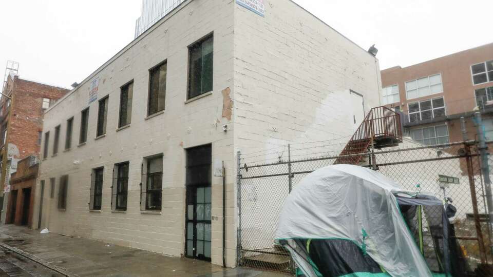 A tent is seen next to building at 457 Minna with for sale signs on the exterior on Monday, December 16, 2024 in San Francisco, Calif.