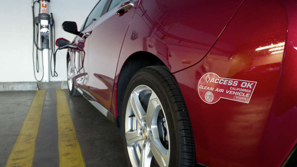 This Wednesday, Oct. 17, 2018 photo shows a clean air vehicle decal on a Chevrolet Volt hybrid car while it charges at a charging station at a parking garage in Los Angeles.