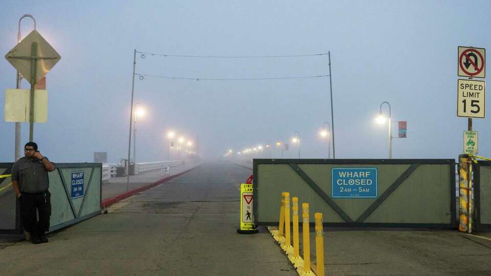 A security guard watches the entrance to the closed Santa Cruz Wharf in Santa Cruz, Calif., Monday, Dec. 23, 2024. (AP Photo/Nic Coury)