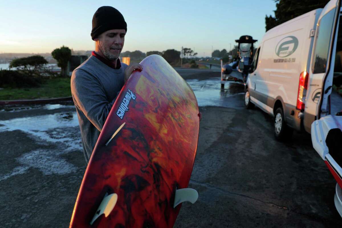 Peter Mel, 50-year-old Santa Cruz surfer, holds his favorite board as he stows his gear after a day surfing Mavericks outside Half Moon Bay, Calif., on Wednesday, January 13, 2021. Mel accomplished some historic rides at Mavericks over the weekend.