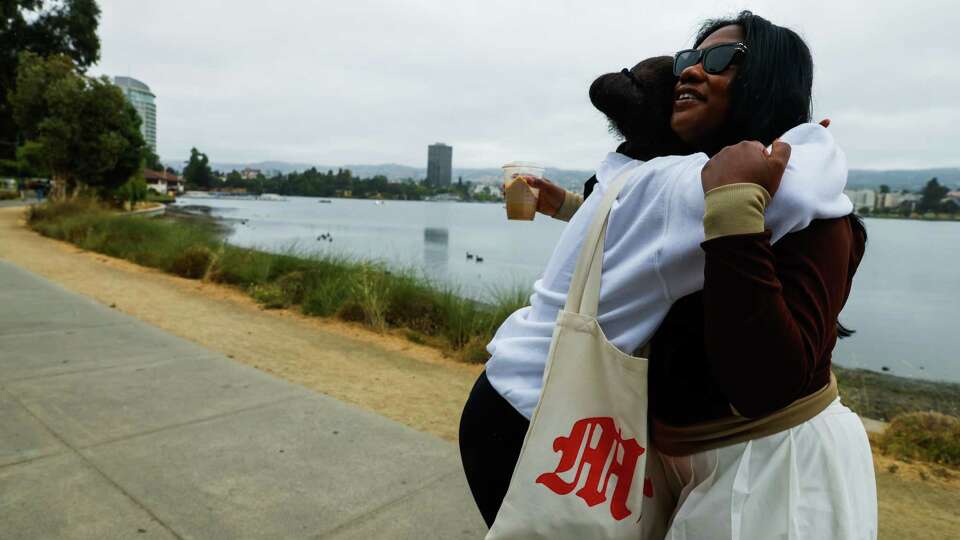 Ashley Hughes, right, hugs friend Myanna Kelly as Kelly says goodbye while Hughes leads a walking club for her TikTok followers at Lake Merritt in Oakland, Calif. on Saturday, July 27, 2024.