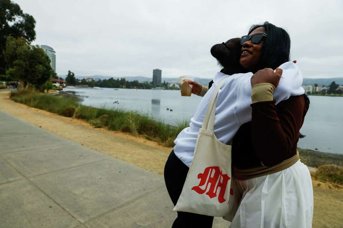 Ashley Hughes, right, hugs friend Myanna Kelly as Kelly says goodbye while Hughes leads a walking club for her TikTok followers at Lake Merritt in Oakland, Calif. on Saturday, July 27, 2024.