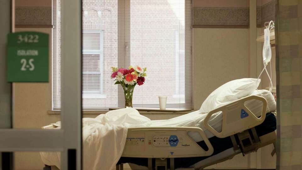 Vacant hospital bed in room with flowers and IV bag