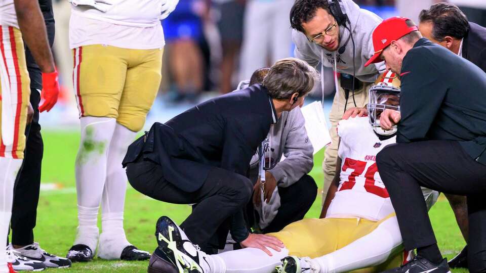 Miami Dolphins head coach Mike McDaniel talks to injured San Francisco 49ers offensive lineman Jaylon Moore (76) as he sits on the field during an NFL football game, Sunday, Dec. 22, 2024, in Miami Gardens, Fla. (AP Photo/Doug Murray)