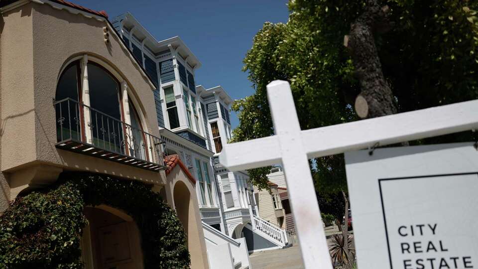 Homes are seen next to a realty company’s sign in front of home for sale on Wednesday, May 22, 2024 in San Francisco, Calif.