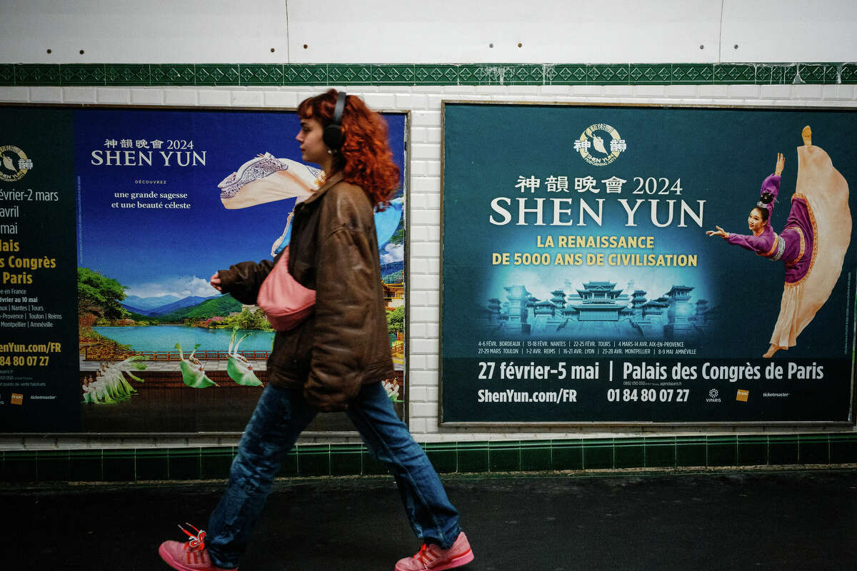 This photograph taken on March 1, 2024, shows a woman walking past posters of the Shen Yun dance show in a metro station in Paris. Dancers dressed in colourful costumes gracefully twirl in front of digitised landscapes of China, with an ambiguous message in the background: since 2006, the Chinese-American company Shen Yun, currently on tour in France, has used its grandiose shows to spread vehement criticism of Beijing and conservative rhetoric around the world. 