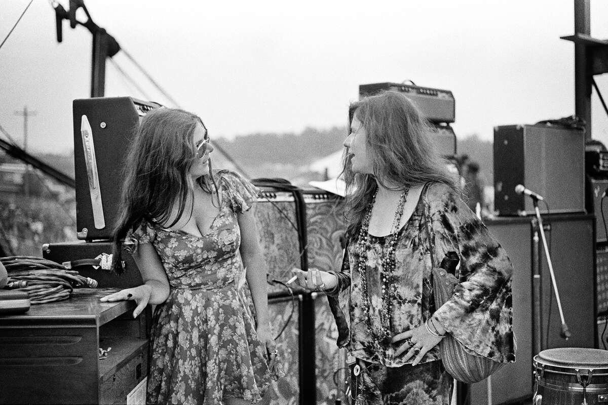 Peggy Caserta, left, speaks with Janis Joplin onstage at Woodstock in August of 1969.