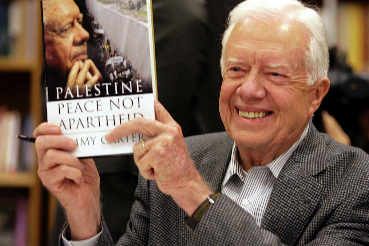 Former President Jimmy Carter holds a copy of his book, “Palestine: Peace, Not Apartheid, ” at a book signing in Tempe, Ariz., on Dec. 12, 2006. 