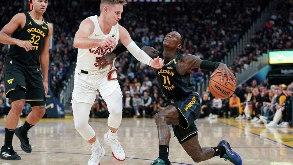 Golden State Warriors guard Dennis Schroder, right, moves the ball while defended by Cleveland Cavaliers guard Sam Merrill (5) during the first half an NBA basketball game Monday, Dec. 30, 2024, in San Francisco. (AP Photo/Kavin Mistry)