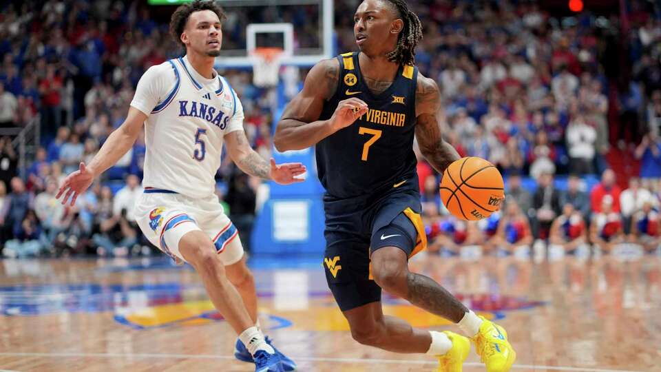 West Virginia guard Javon Small (7) drives past Kansas guard Zeke Mayo (5) during the second half of an NCAA college basketball game, Tuesday, Dec. 31, 2024, in Lawrence, Kan. West Virginia won 62-61