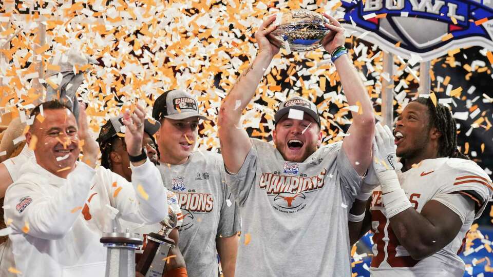 Texas quarterback Quinn Ewers lifts the Peach Bowl trophy after defeating Arizona State 39-31 in double overtime of a NCAA college football playoff quarterfinal game on Wednesday, Jan. 1, 2025, in Atlanta.