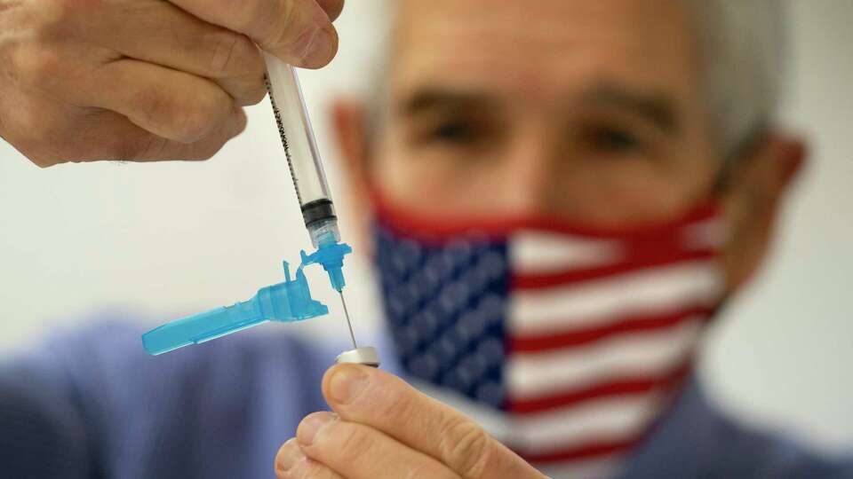 FILE - Dr. Sydney Sewall fills a syringe with the COVID-19 vaccine at the Augusta Armory, Dec. 21, 2021, in Augusta, Maine.