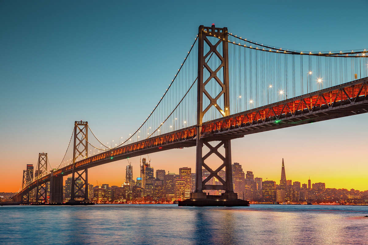 The Oakland Bay Bridge is seen illuminated at sunset.