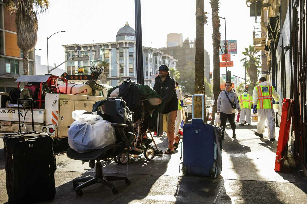 The Department of Public Works cleans the streets as a homeless man named Justin (center) moves his belongings during a sweep on 6th Street in San Francisco on Monday, Oct. 14, 2024.