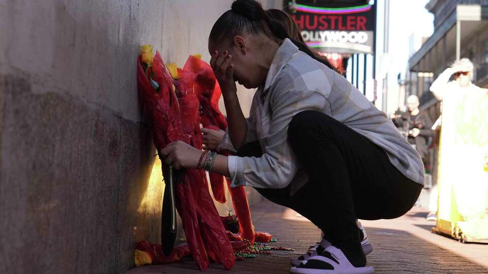 Samantha Petry places flowera at a memorial on Canal and Bourbon Street, Thursday, Jan. 2, 2025 in New Orleans. (AP Photo/George Walker IV)