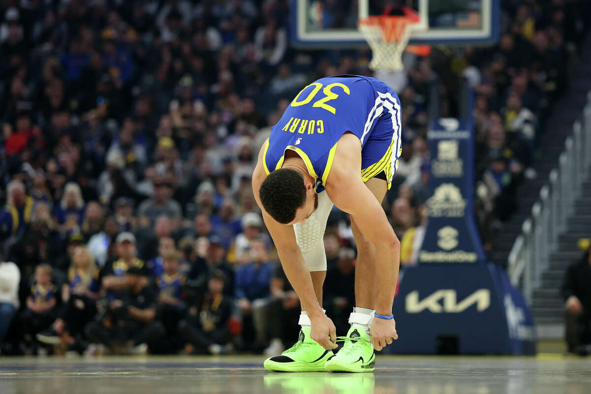 Stephen Curry of the Golden State Warriors ties his sneakers during their game against the Phoenix Suns in the first half at Chase Center on December 28, 2024 in San Francisco, California.