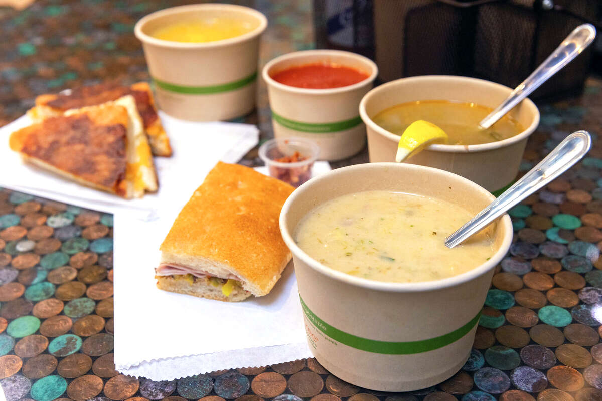 (Counter clockwise from bottom center) The Bodega Bay Clam Chowder, Caldo Verde Linguica, Collards and Potato with Lemon soup, Tomato soup, Broccoli Cheddar, Shmelty grilled cheese sandwich, and La Magnifica sandwich at the Rusty Ladle in San Francisco, Calif. on Dec. 6, 2024.