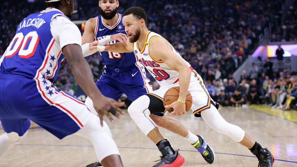 Golden State Warriors’ Stephen Curry drives between Philadelphia 76ers’ Reggie Jackson and Caleb Martin in 1st quarter during NBA game at Chase Center in San Francisco on Thursday, January 2, 2025.