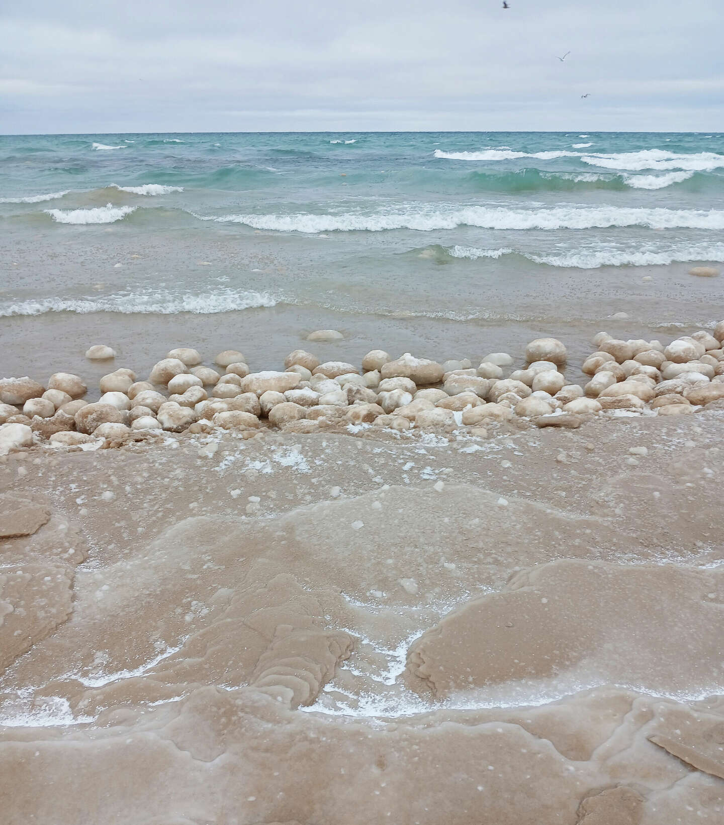 Lake Michigan ice balls roll into Manistee's lakeshore after high wind