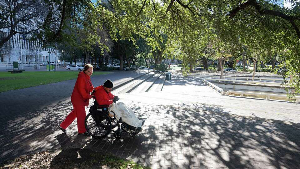 Meagan Garrett, 20, pushes her husband, Damacio Perez, 22, in a wheelchair as they try to stay warm in Tranquillity Park in Downtown Houston, TX on Monday, January 6, 2024. The Houston area is experiencing its coldest temperatures in nearly a year and the city has not opened warming centers.