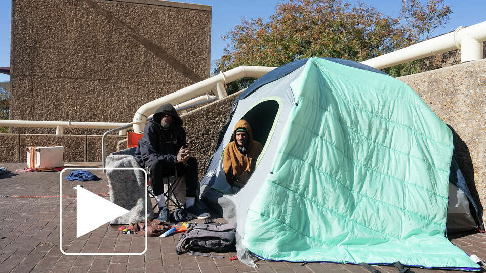 Richard Deas, 40, center, tries to stay warm in Tranquillity Park in Downtown Houston, TX on Monday, January 6, 2024. The Houston area is experiencing its coldest temperatures in nearly a year and the city has not opened warming centers. 