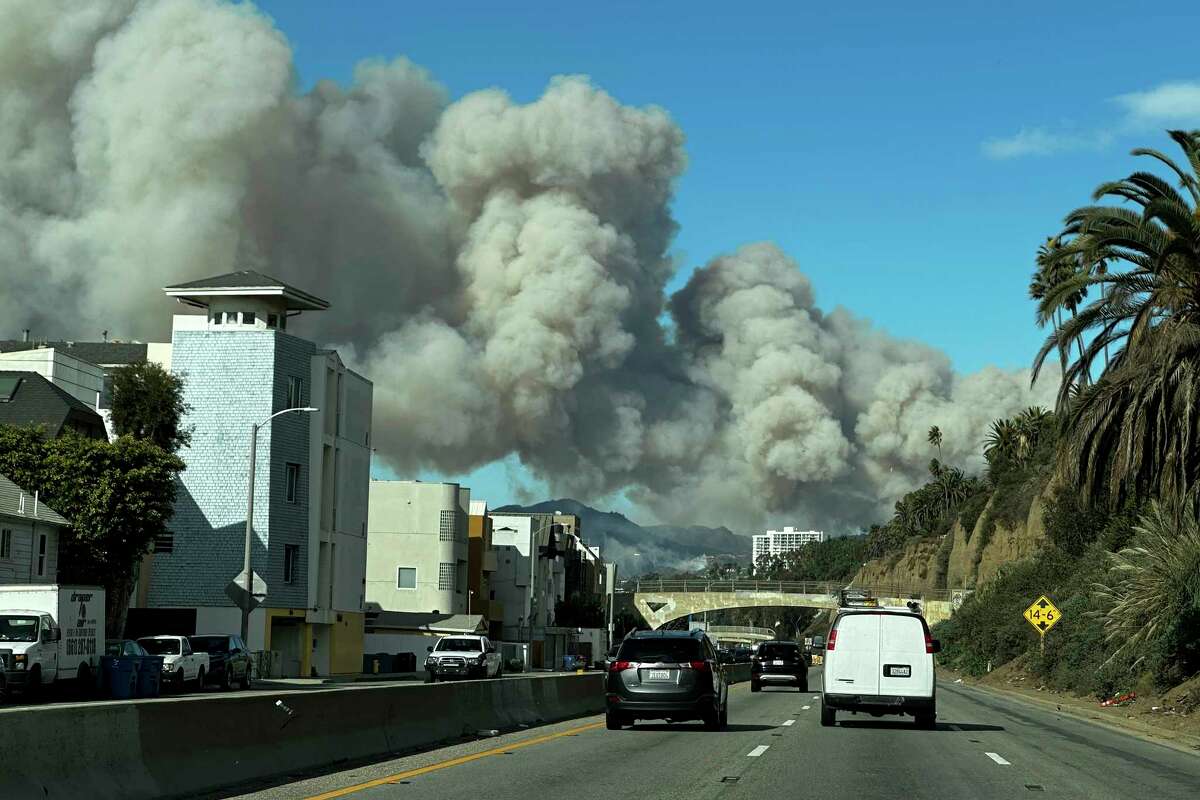 Heavy smoke from a brush fire in the Pacific Palisades rises over the Pacific Coast Highway in Santa Monica, Calif., on Tuesday, Jan. 7, 2025.