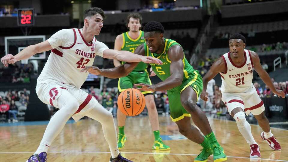 Oregon guard TJ Bamba (5) drives to the basket against Stanford forward Maxime Raynaud (42) and guard Jaylen Blakes (21) during the second half of an NCAA college basketball game in the San Jose Tip-Off in San Jose, Calif., Saturday, Dec. 21, 2024. (AP Photo/Jeff Chiu)