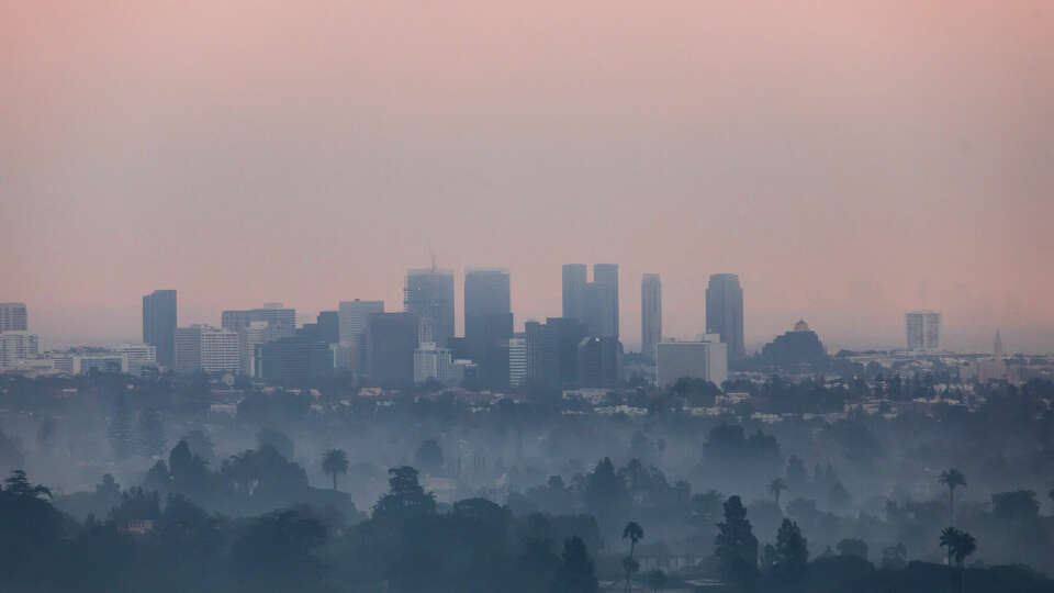 Burned trees and wildfire smoke from the Palisades Fire are seen from Will Rogers State Park with downtown Los Angeles in the distance, on January 9, 2025 in the Pacific Palisades neighborhood of Los Angeles, California. Multiple wildfires fueled by intense Santa Ana Winds are burning across Los Angeles County. At least five people have been killed, and over 25,000 acres have burned. Over 2,000 structures have also burned and almost 180,000 people are under orders to evacuate. 