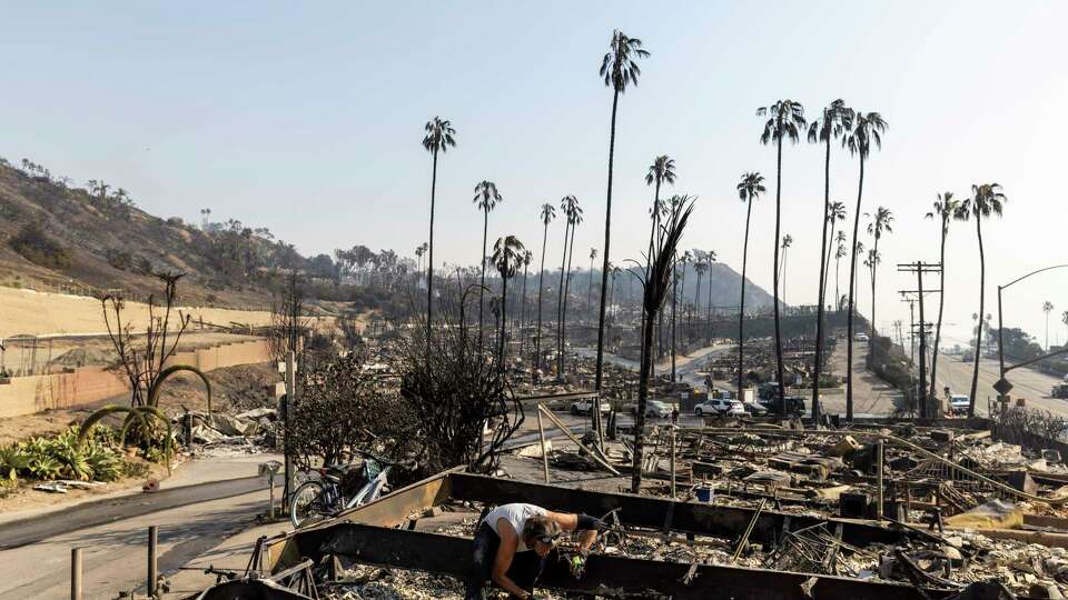 Roger Cohn looks for items amongst his girlfriend Lisa Anderson’s home destroyed by the Palisades Fire in Pacific Palisades, Calif., Thursday, Jan. 9, 2025.