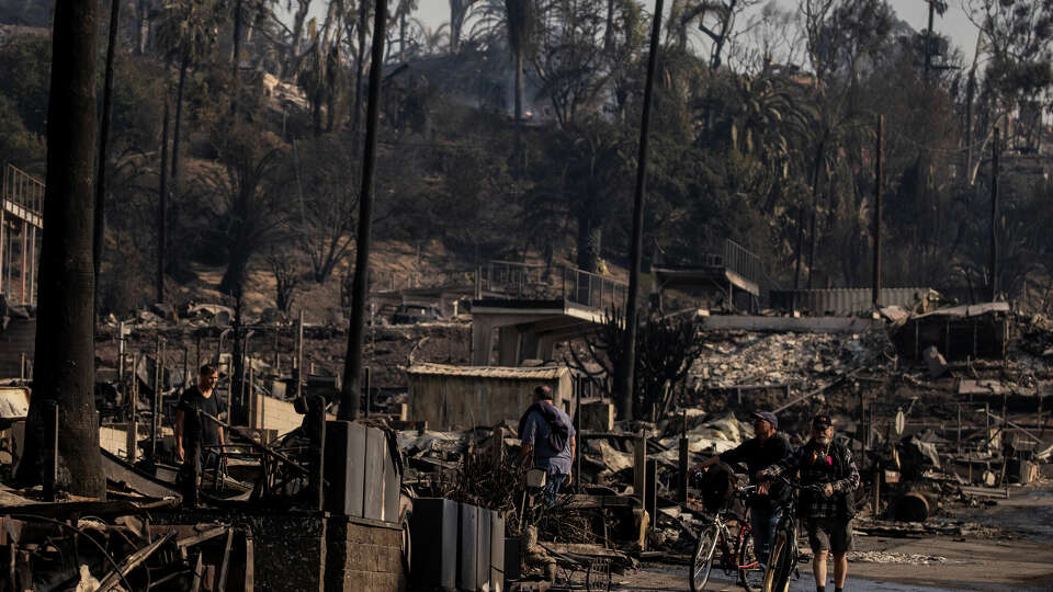 People walk amongst Pacific Palisades Bowl Mobile Estates destroyed by the Palisades Fire in Pacific Palisades, Calif., Thursday, Jan. 9, 2025.